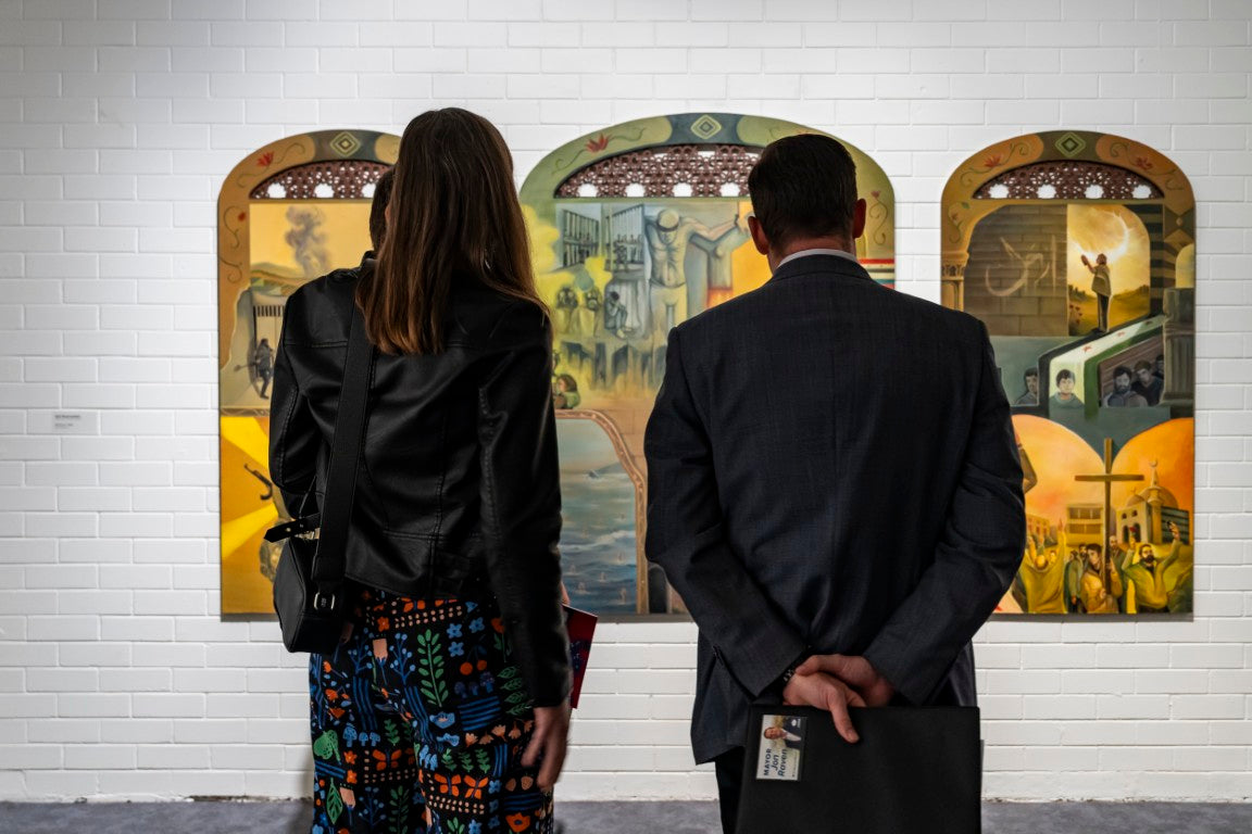 2 Formally dressed people standing in front of the artwork "Windows" a revolutionary Tryptych Collage, on display in Logan Art Gallery. 